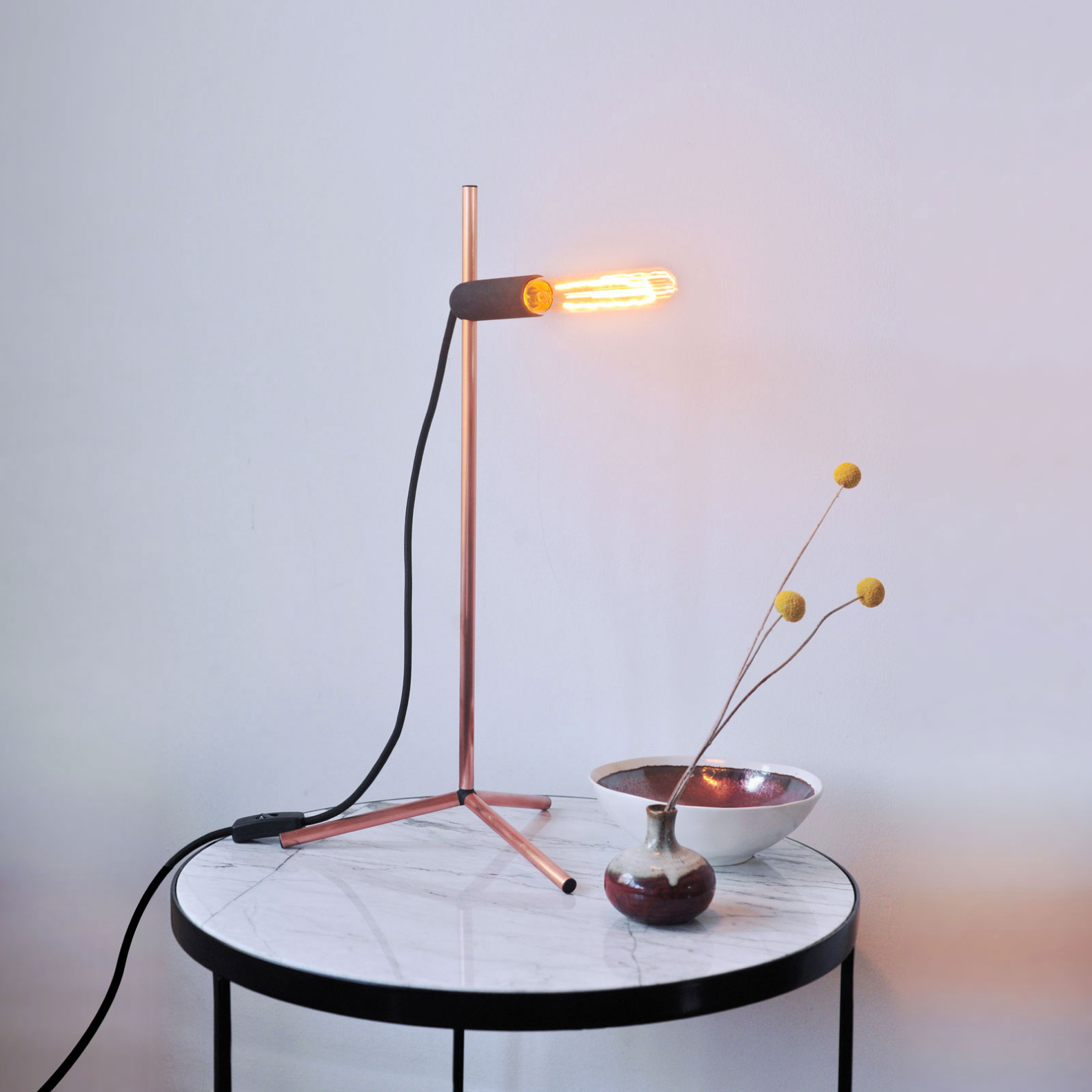 Photograph of the Spire light on a marble side-table with other design objects.